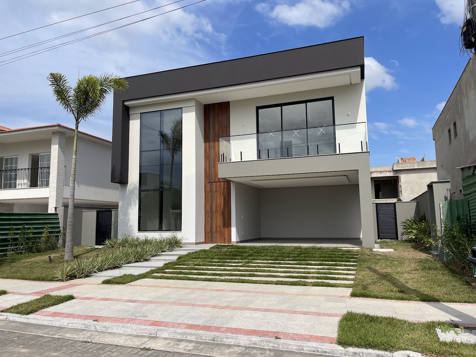 Residência contemporânea com esquadrias pretas e guarda-corpo em vidro